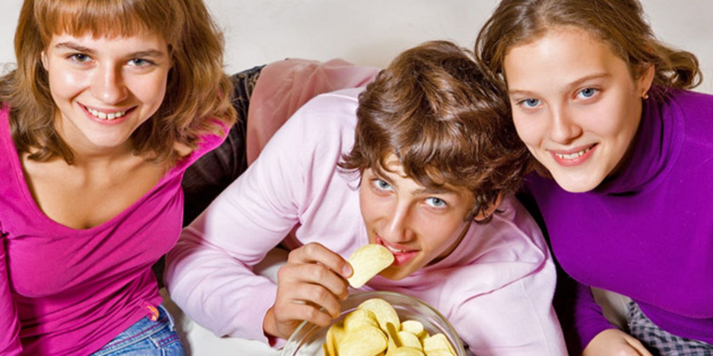Jugendliche essen Chips auf einer Couch