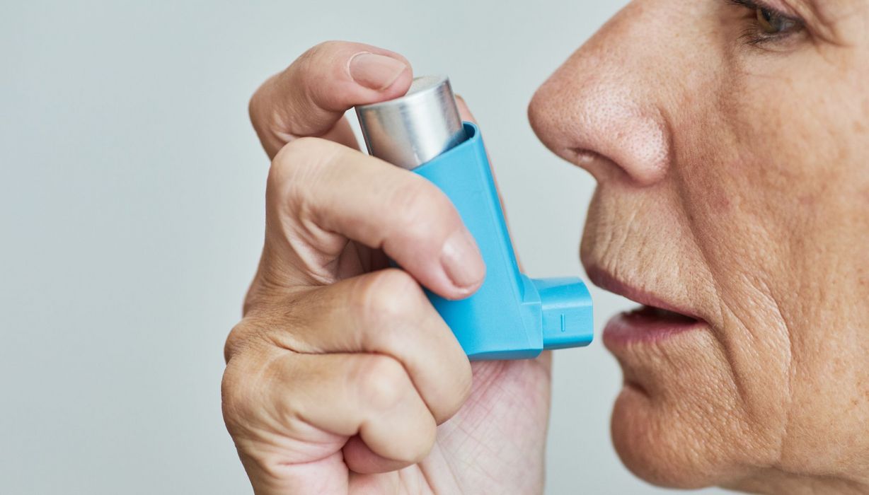 Ältere Frau, nutzt Asthmaspray.
