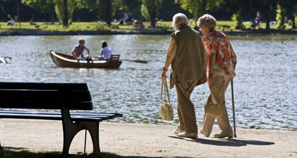 Zwei Seniorinnen gehen an einem Weiher spazieren