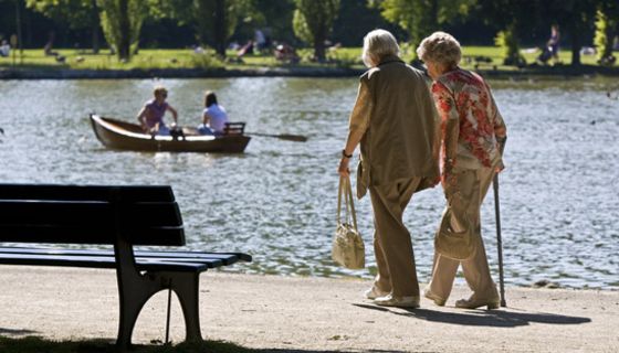 Zwei Seniorinnen gehen an einem Weiher spazieren
