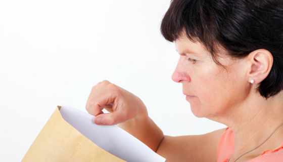 Ältere Frau zieht einen Brief aus einem Umschlag