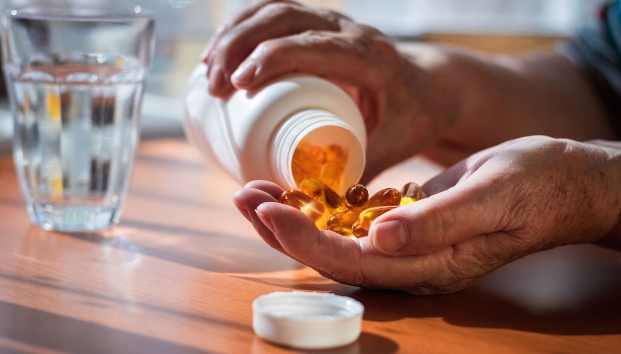 Mann, schüttet sich Tabletten in die Hand.