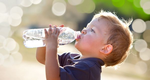 Kind, trinkt Wasser aus einer Flasche
