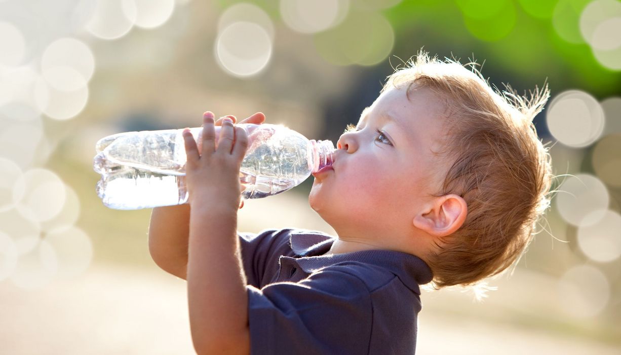 Kind, trinkt Wasser aus einer Flasche