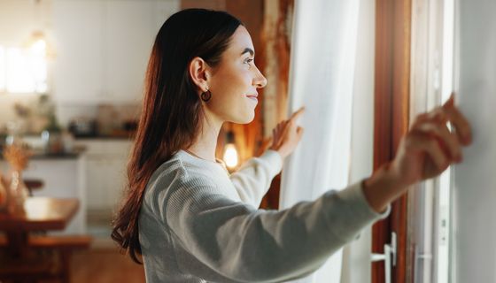 Junge Frau, steht am Fenster und lüftet. 
