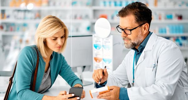 Ein Apotheker berät eine Kundin zu einem Präparat.