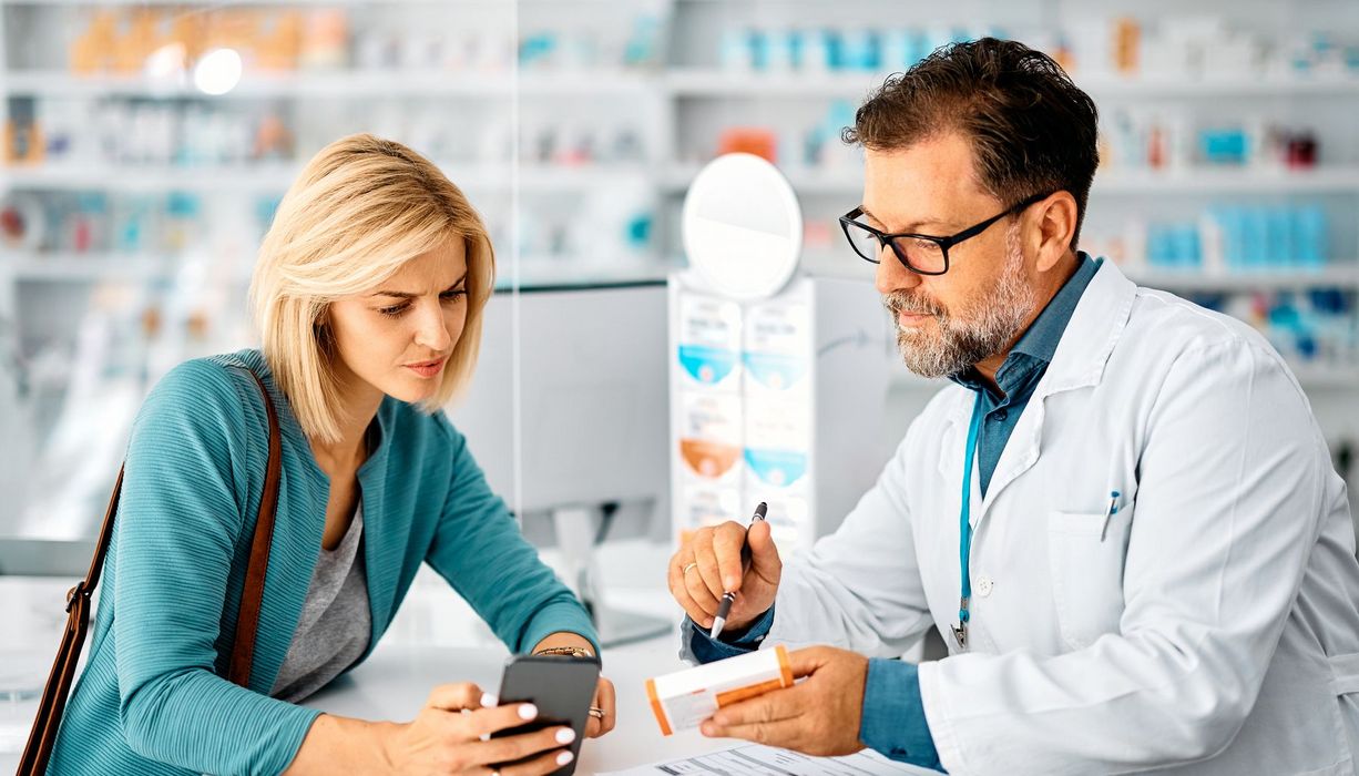 Ein Apotheker berät eine Kundin zu einem Präparat.
