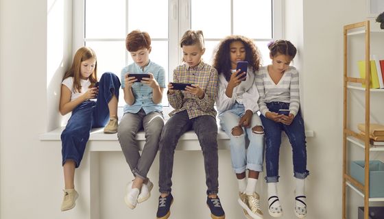 Mehrere Kinder nutzen Smartphone, während sie auf einer Fensterbank sitzen