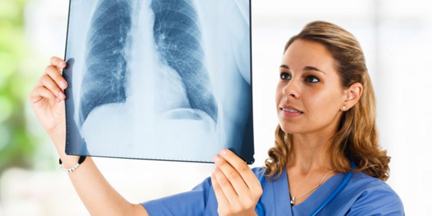 Ärztin betrachtet mit prüfendem Blick das Röntgenbild einer Lunge