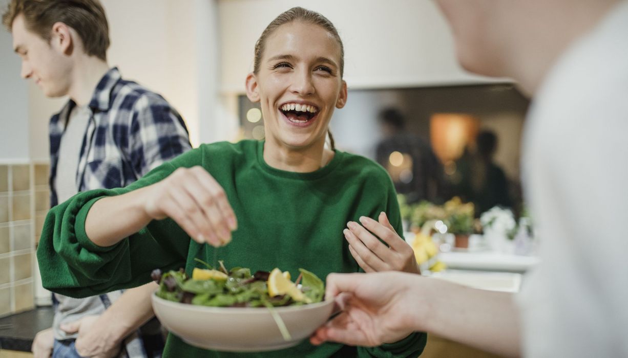 Frau, reicht einen Salat weiter.