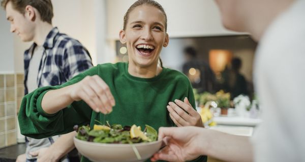 Frau, reicht einen Salat weiter.