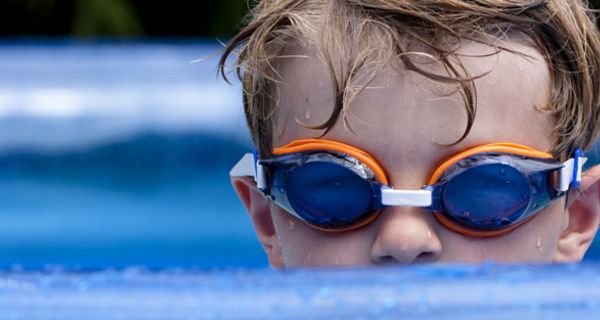 Kleiner Junge mit Schwimmbrille im Freibad