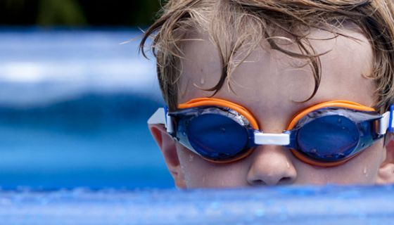 Kleiner Junge mit Schwimmbrille im Freibad