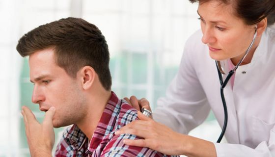 Ärztin horcht hustenden Patienten ab.