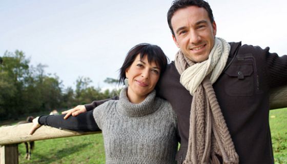 Entspanntes Paar, 40+, lehnt an Pferdekoppel.