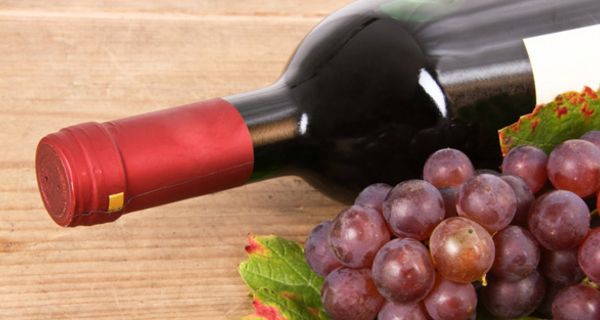 Liegende Flasche Rotwein und rote Weintrauben