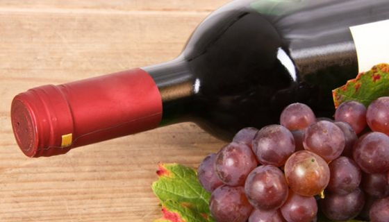 Liegende Flasche Rotwein und rote Weintrauben