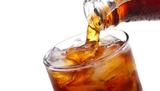 Großaufnahme Cola mit Eis im Glas, Colaflasche beim Einschenken in das Glas