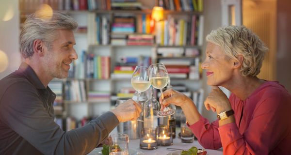 Frau und Mann stoßen an bei einem gemütlichen Abendessen.