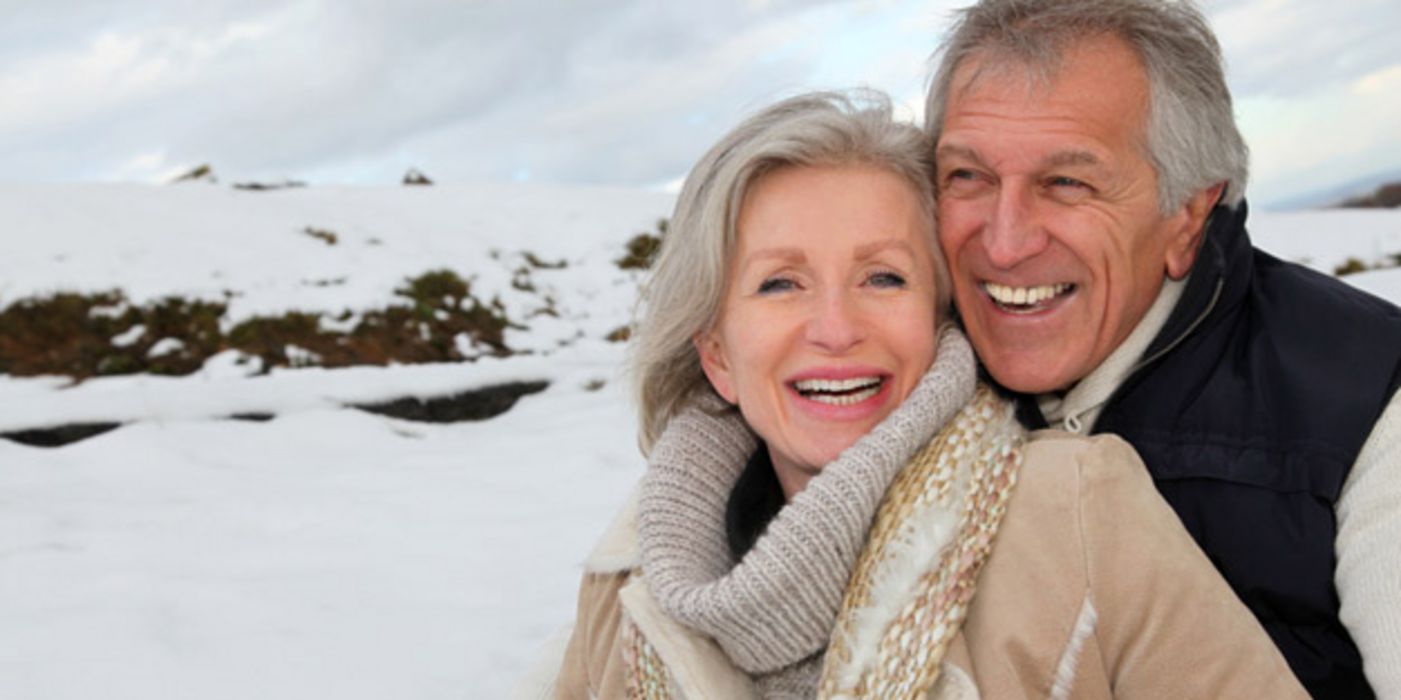 Älteres lachendes Paar vor Schneelandschaft