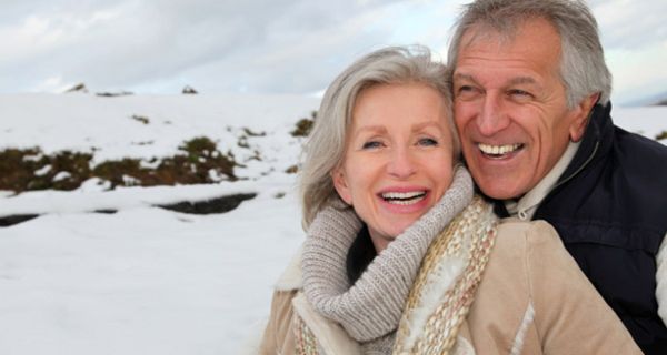 Älteres lachendes Paar vor Schneelandschaft