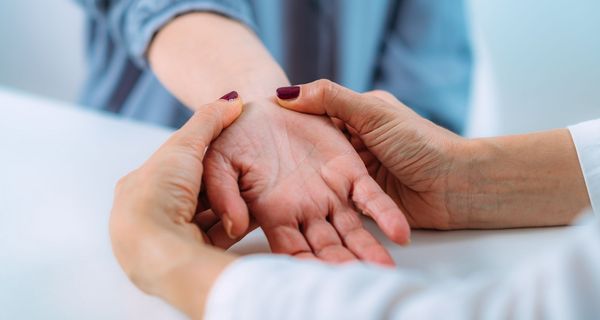 Arzt, behandelt das Handgelenk einer Patientin.