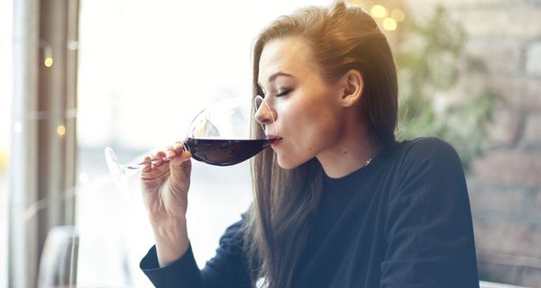 Junge Frau trinkt ein großes Glas Rotwein.