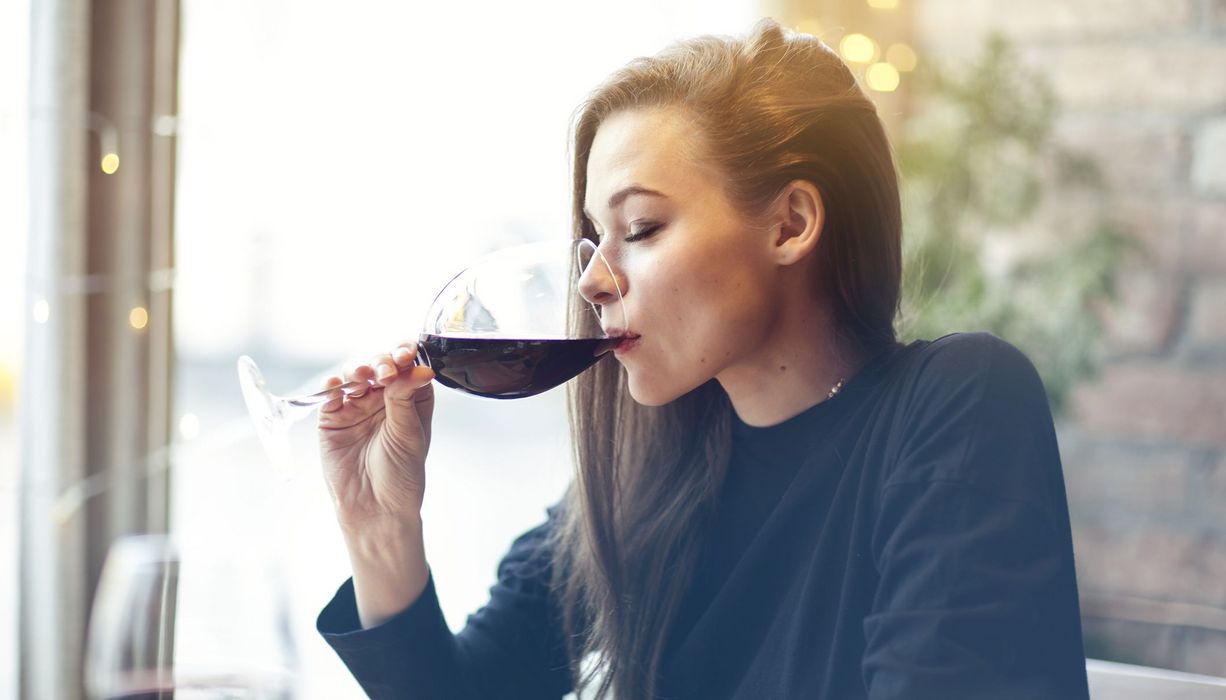 Junge Frau trinkt ein großes Glas Rotwein.