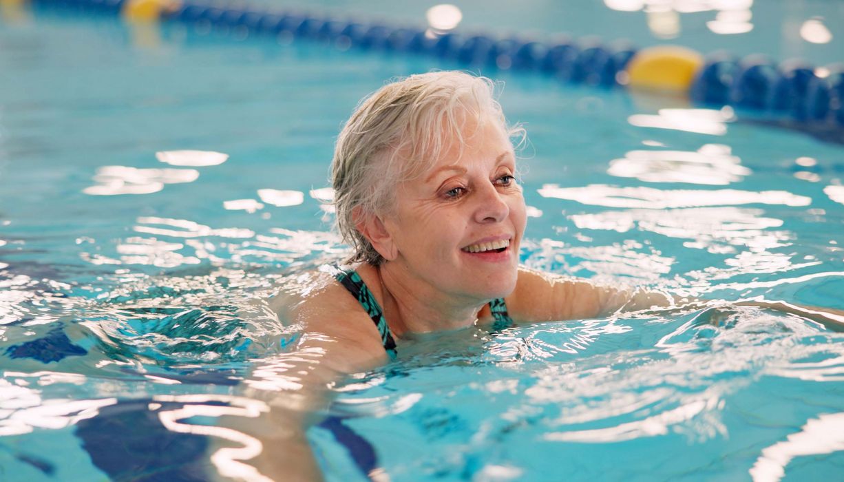 Ältere Dame schwimmt im Schwimmbad.