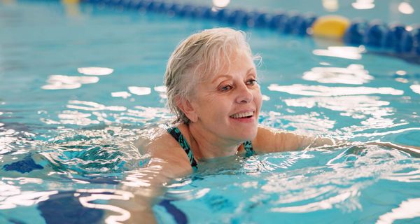 Ältere Dame schwimmt im Schwimmbad.