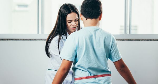 Ärztin misst Bauchumfang eines leicht übergewichtigen Kindes
