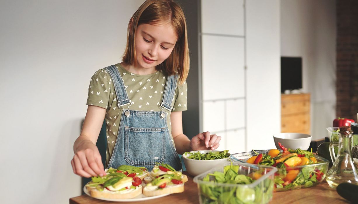 maedchen belegt Brote mit Salat und Gemuese