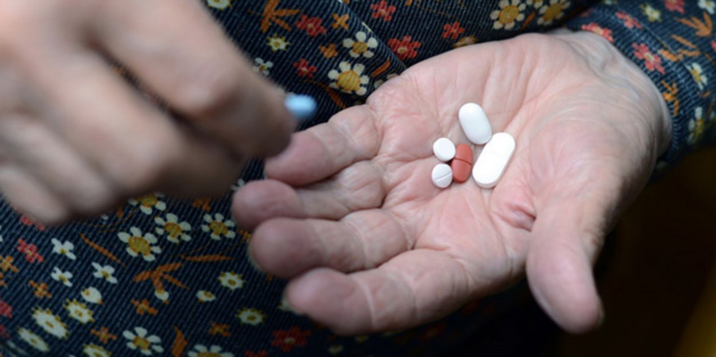 Seniorin hält mehrere Tabletten in der offenen Hand