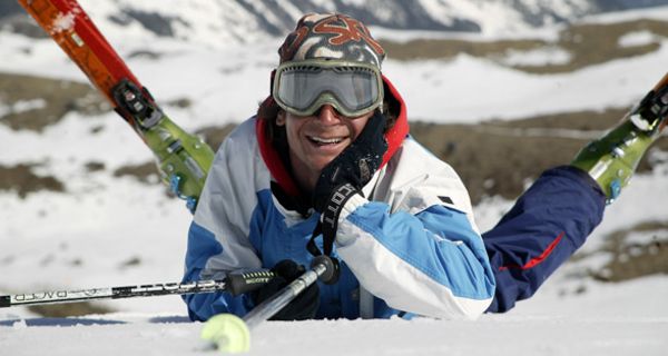 Skifahrer mir Skibrille liegt auf dem Bauch im Schnee, die Skier sind gekreuzt