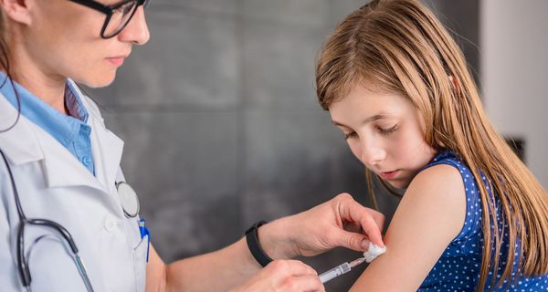 Ärztin impft ca. 10 Jahre altes Mädchen.