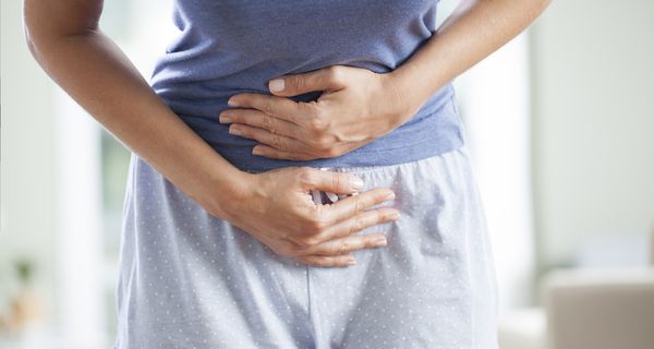 Junge Frau, hält sich den Bauch.