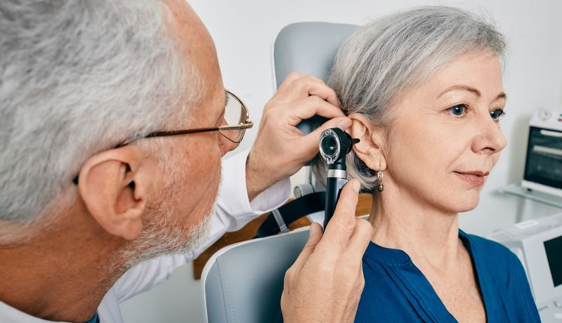 Ein Arzt untersucht das Ohr einer älteren Frau