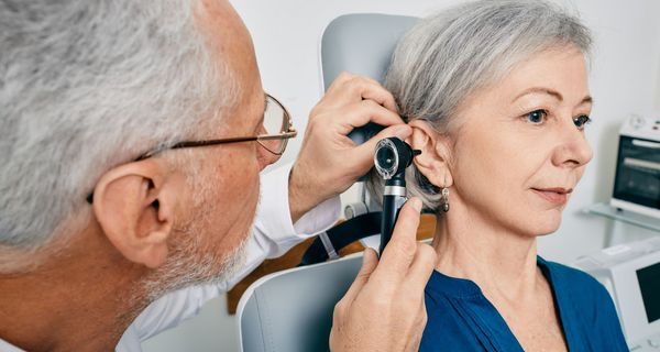 Ein Arzt untersucht das Ohr einer älteren Frau