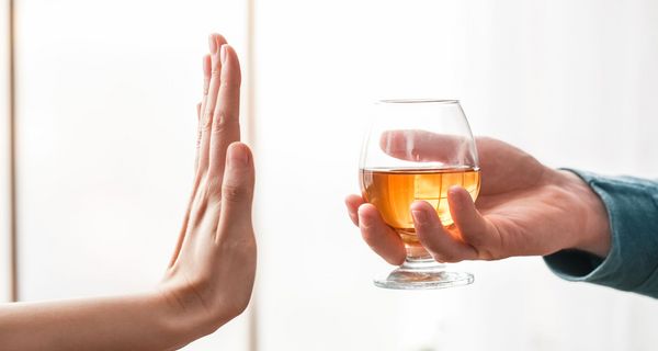 Alkohol wird angeboten. Hand macht eine ablehnende Geste