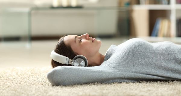 Junge Frau, liegt auf dem Boden mit Kopfhörern und entspannt.