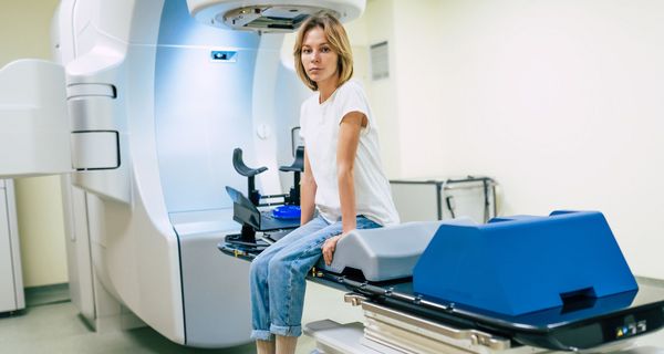 Junge Frau sitzt auf der Liege eines Bestrahlungsgeräts.