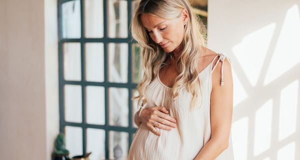 Junge schwangere Frau, schaut auf ihren Babybauch.