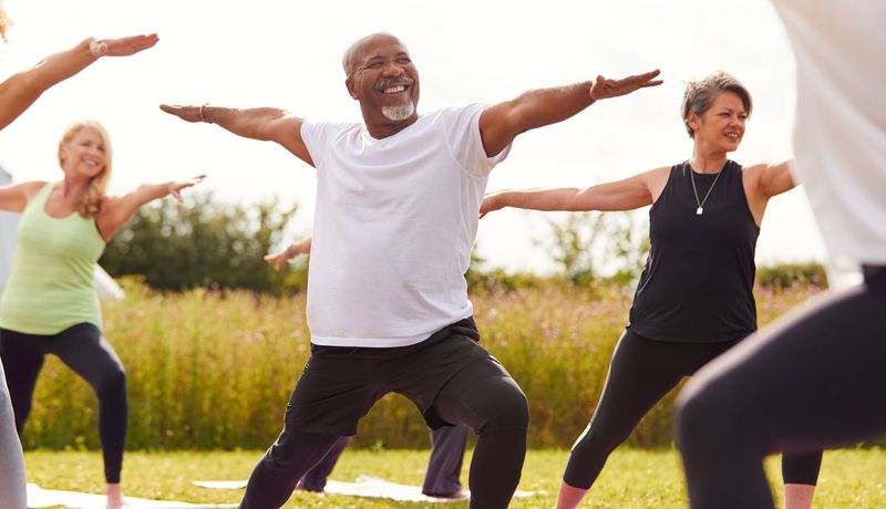 Mann macht in einer Gruppe draußen Yoga. 