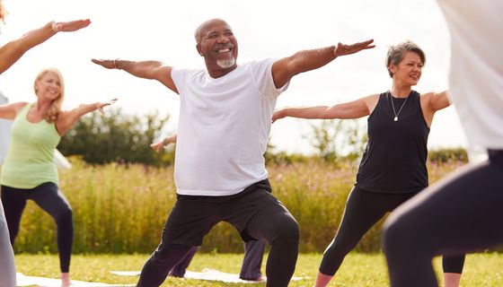 Mann macht in einer Gruppe draußen Yoga. 