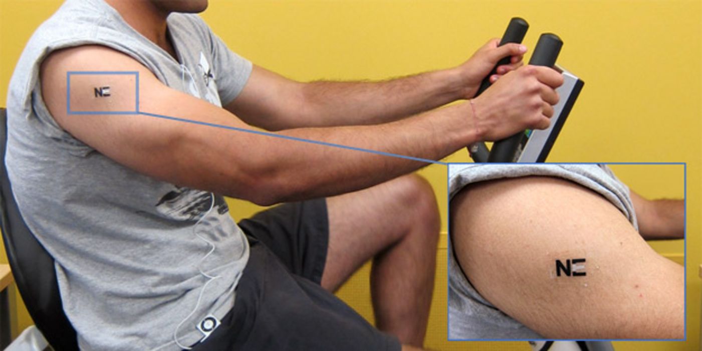 Mann trainiert auf Fahrradergometer mit Tattoo-Sensor am Oberarm.