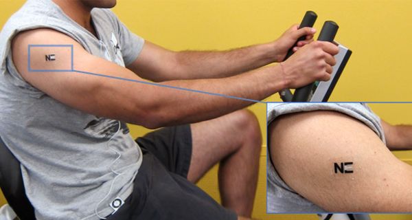 Mann trainiert auf Fahrradergometer mit Tattoo-Sensor am Oberarm.