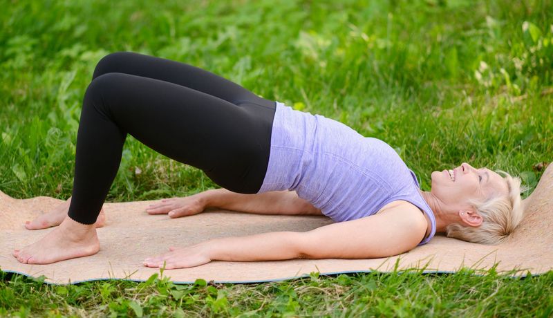 Beckenbodentraining im Park: Eine Frau in der Brückenposition.