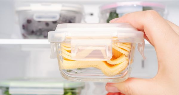 Frau, hält eine Tupperdose mit Käse in der Hand.