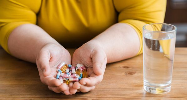 Frau, übergewichtig, hält Tabletten in ihren Händen.