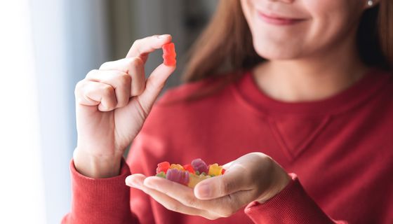 Frau, hält Gummibärchen in die Kamera.